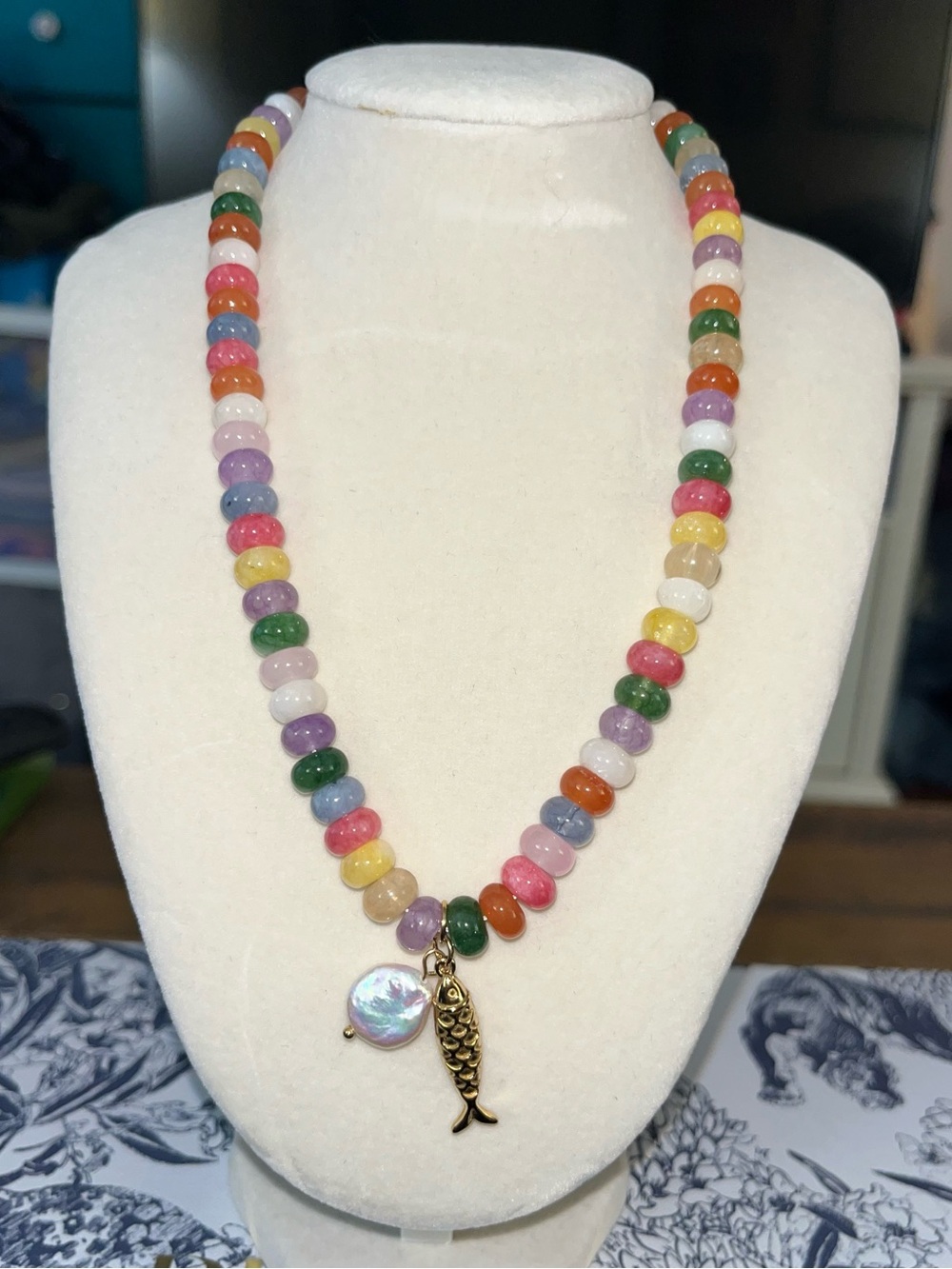 🎏 Multi-colored beaded necklace with gold fish charm and mother-of-pearl accent.